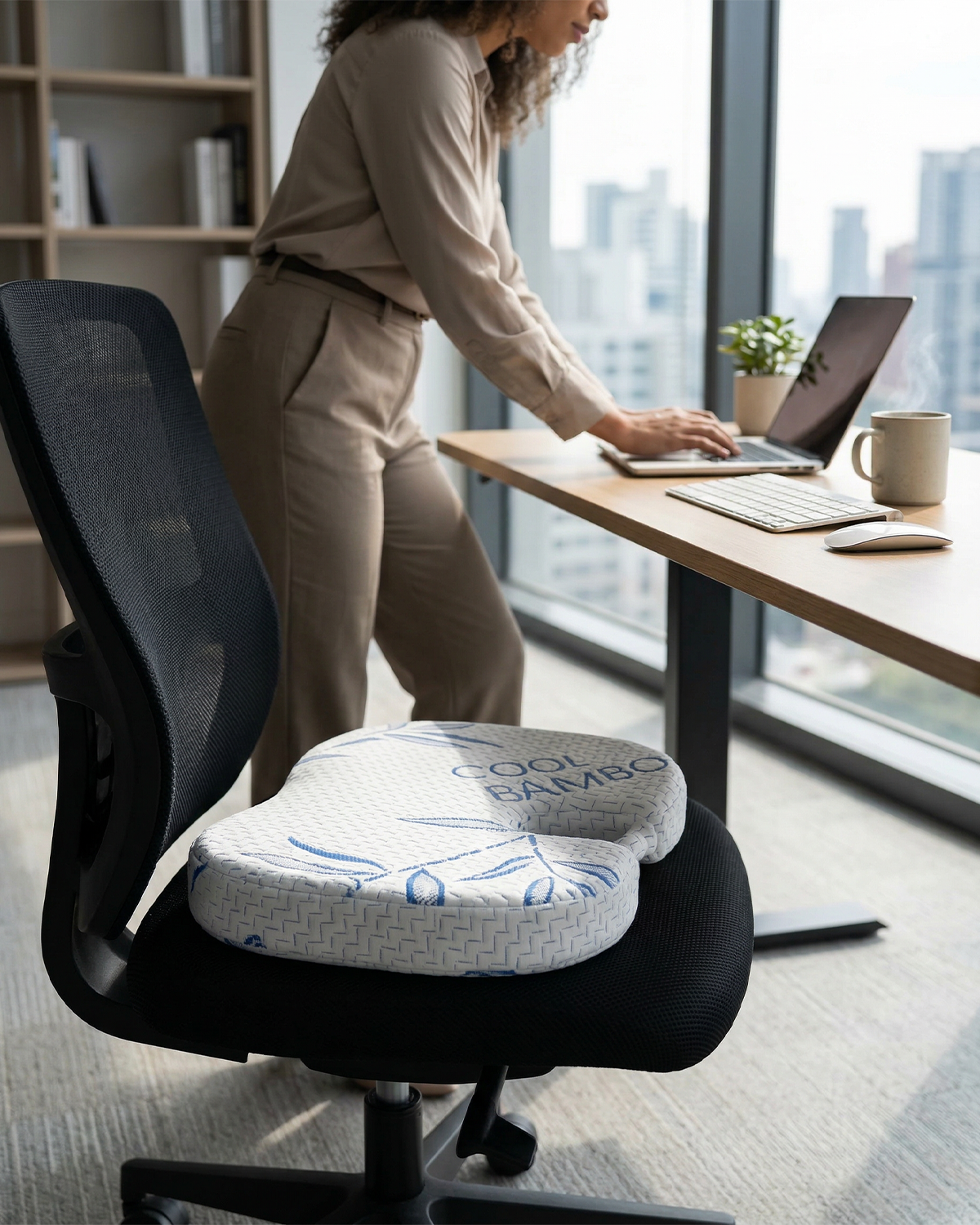 Person using a laptop at a desk with a Cool Bamboo seat cushion on an office chair.